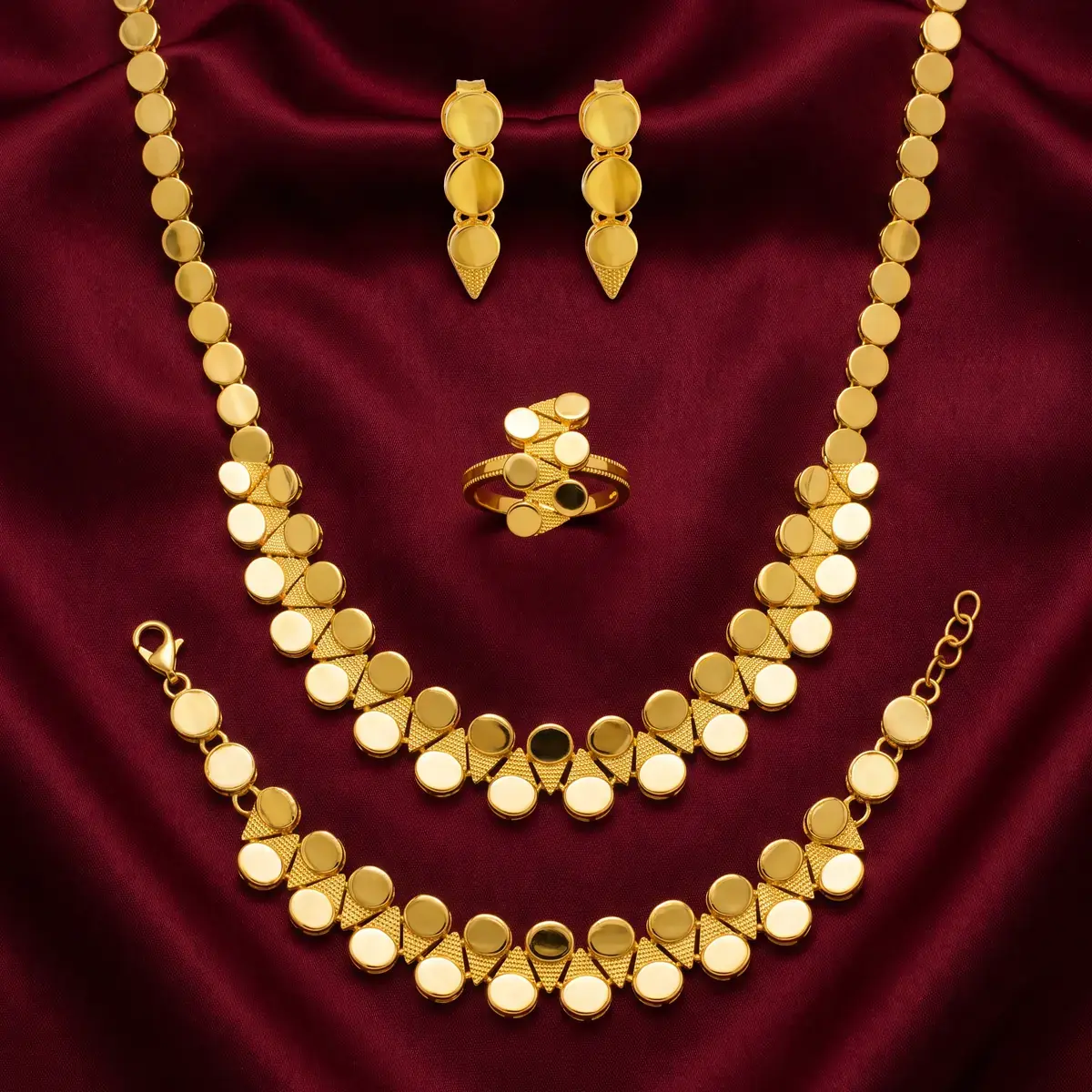 Row Disc Set in 21K gold on oxblood satin: a necklace, a bracelet, a pair of earrings and a ring, all of flat polished discs